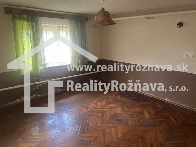 A room in a family house with a wooden floor design and green curtains.