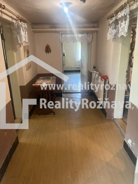 A hallway in a family house with a wooden decor floor, a table, and decorations.