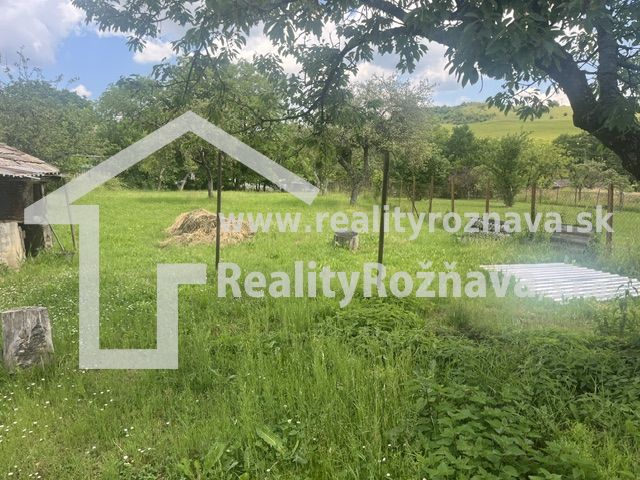 A garden with grass and trees near a family house in Rudná.