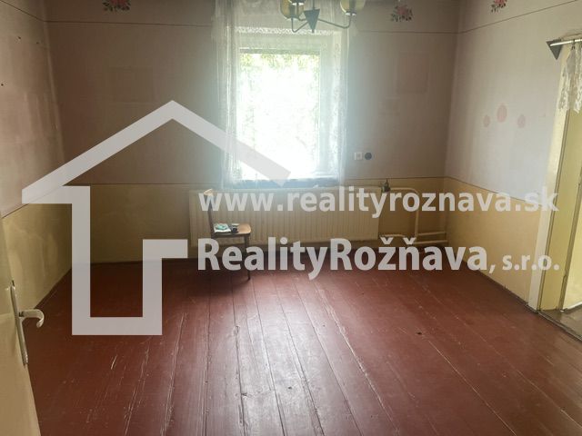 A room in a family house with a wooden floor, pastel-colored walls, a window with a white curtain.