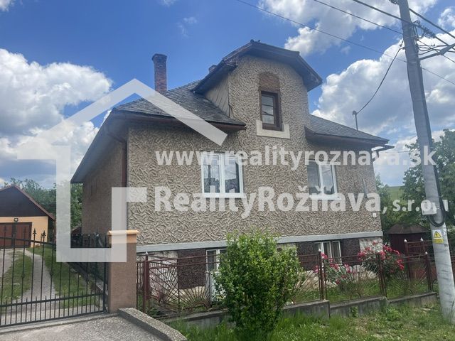 A family house in Rudná with a two-story facade, a fenced plot, and a blue sky.