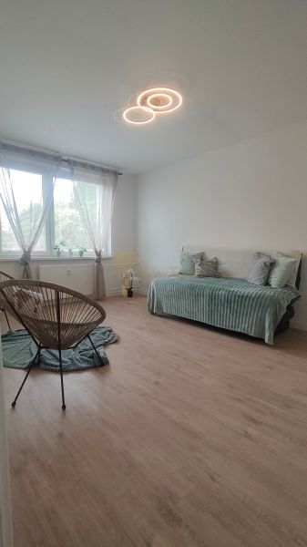 A bright room with a sofa, an armchair, and a wooden decor floor in a 4-room apartment.