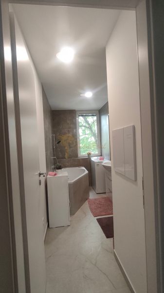 A bathroom with a shower, bathtub, sink, and washing machine in a 4-room apartment.