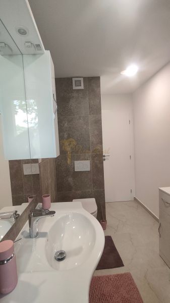 A bathroom in a 4-room apartment with a light sink and dark tiles.