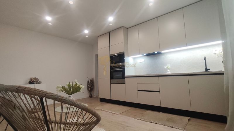 A kitchen in a 4-room apartment with a wooden decor floor and elegant lighting.