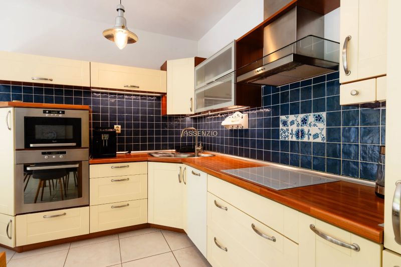 A kitchen with dark blue tiles and built-in appliances in a two-room apartment.