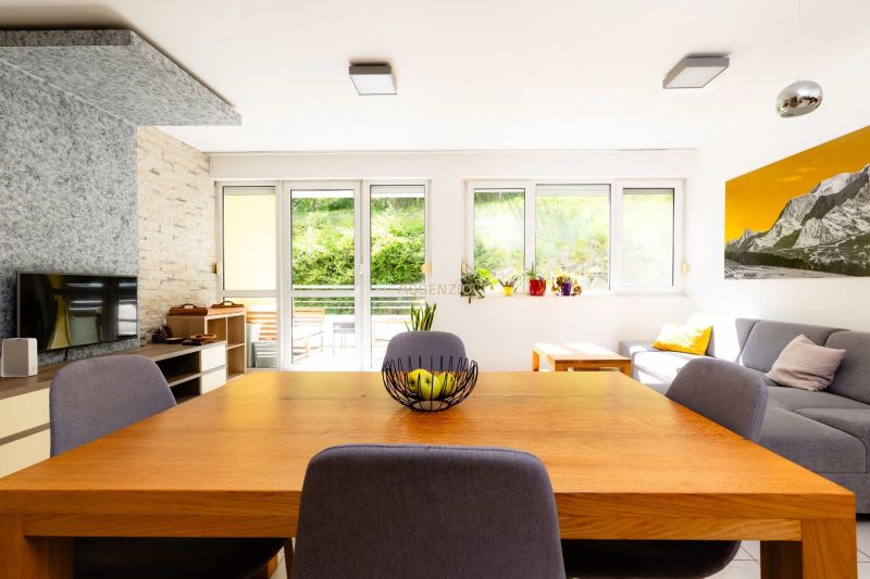 Living room in a two-room apartment with a wooden table and a sofa, view of the terrace.