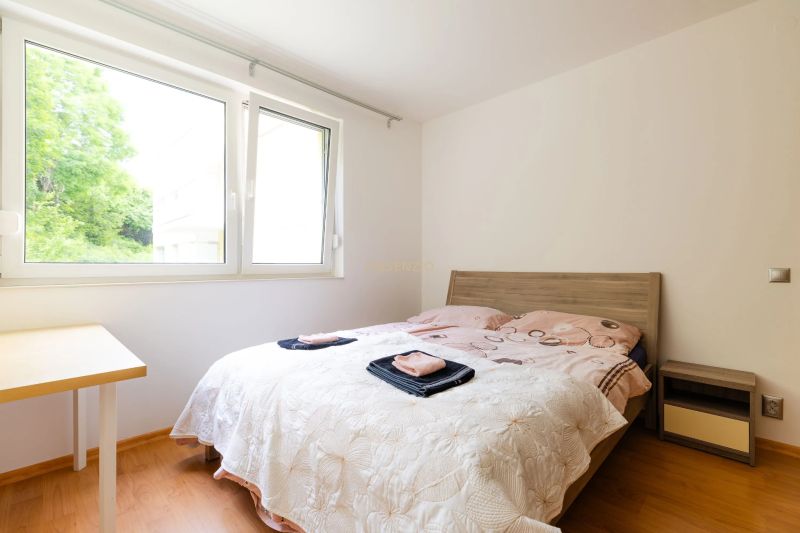 A bedroom in a 2-room apartment with a window, a bed, and a floor with a wooden decor.
