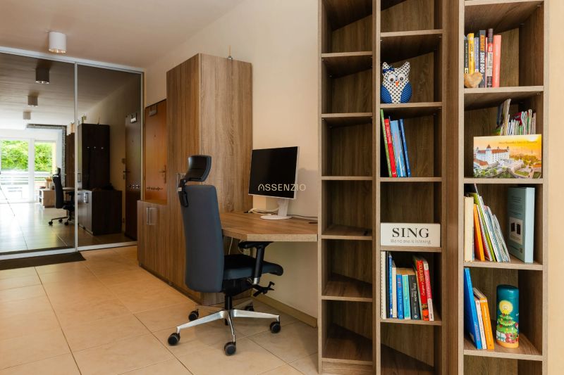 A library and a work corner with a chair in a 2-room apartment with a view of the balcony.