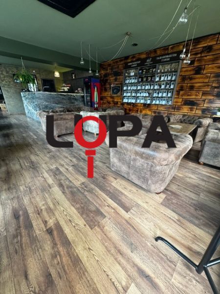 Interior of commercial spaces with comfortable seating, walls with wooden decor, and flooring with wooden decor.