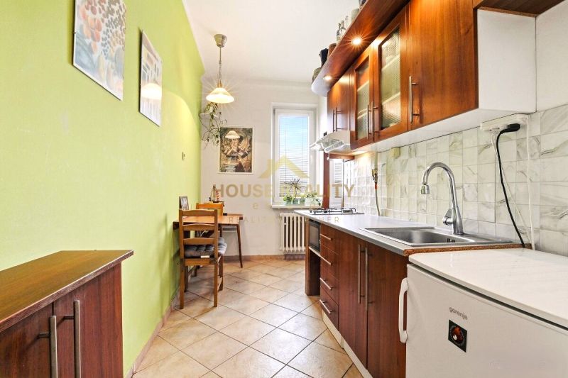 A kitchen in a 2-room apartment with a wooden decor and a green wall, seating at the table.