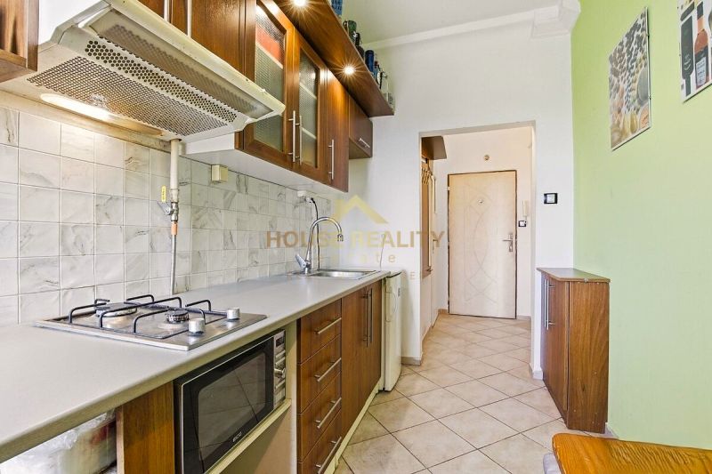 A kitchen in a 2-room apartment with a gas stove, microwave, and storage space.