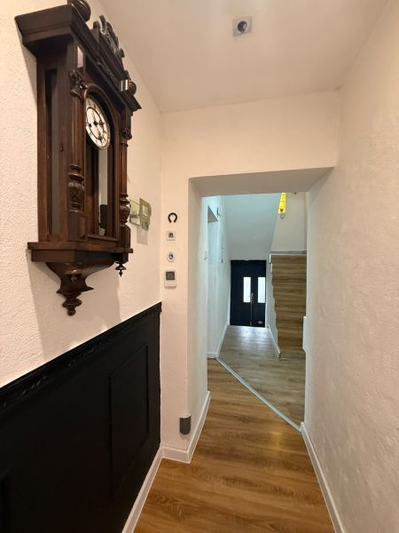 A hallway of a family house with a clock and a wooden decor floor.