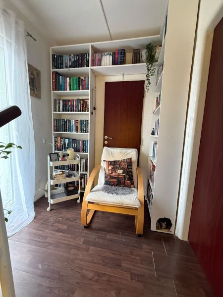 A library in a family house with an armchair, shelves, and a wooden decor floor.