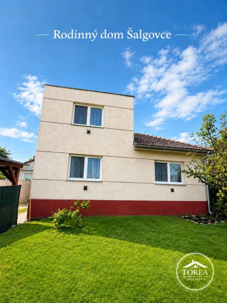 A family house in Šalgovce with a well-maintained lawn under a blue sky.