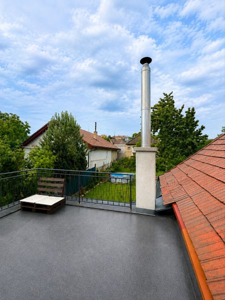 The rooftop terrace of a family house in Šalgovce with a chimney and a view of the garden.