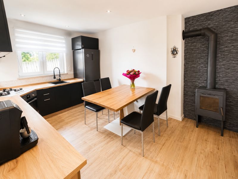 A kitchen in a family house with tiles, a wooden decor floor, and a dining table.