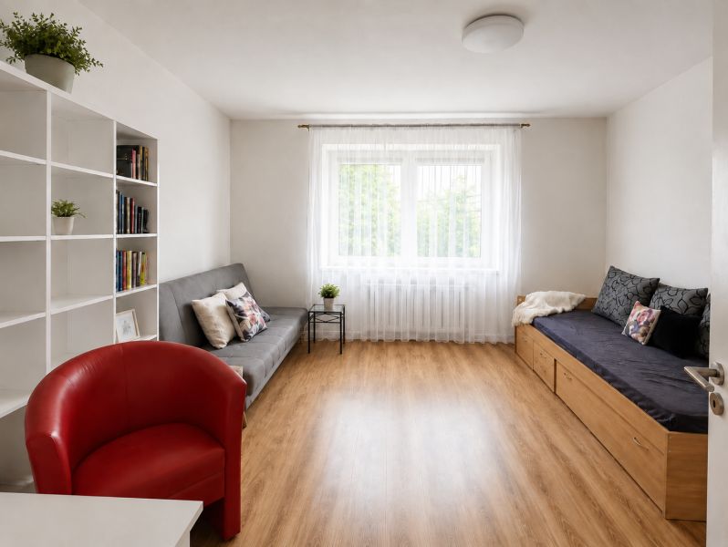Living room with a sofa, an armchair, shelves, and a wooden decor floor in a family house.