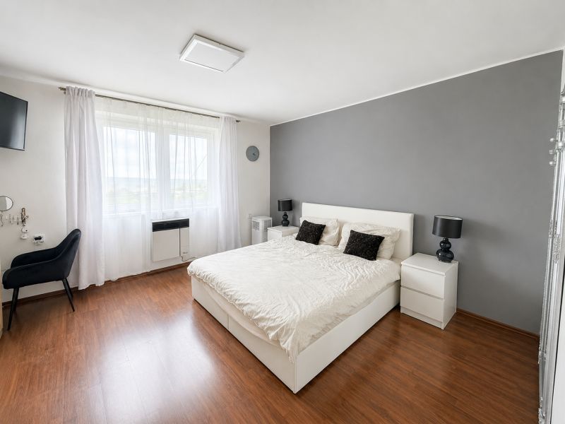 A bedroom in a family house with white furniture and a wooden decor floor.