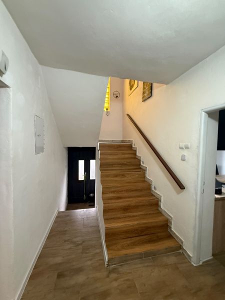 A hallway in a family house with a staircase and a wooden decor floor.