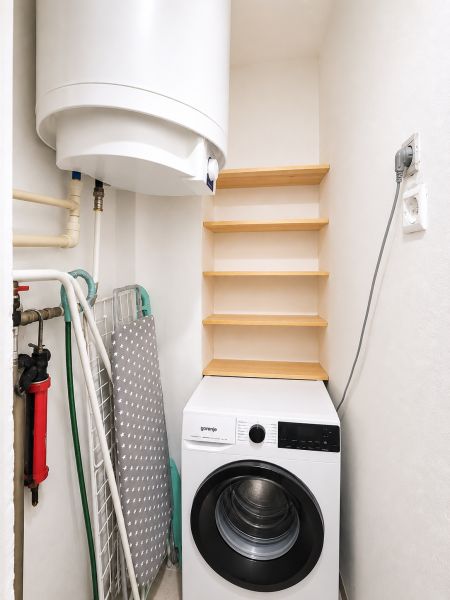 Laundry room in a family house with shelves and a washing machine.