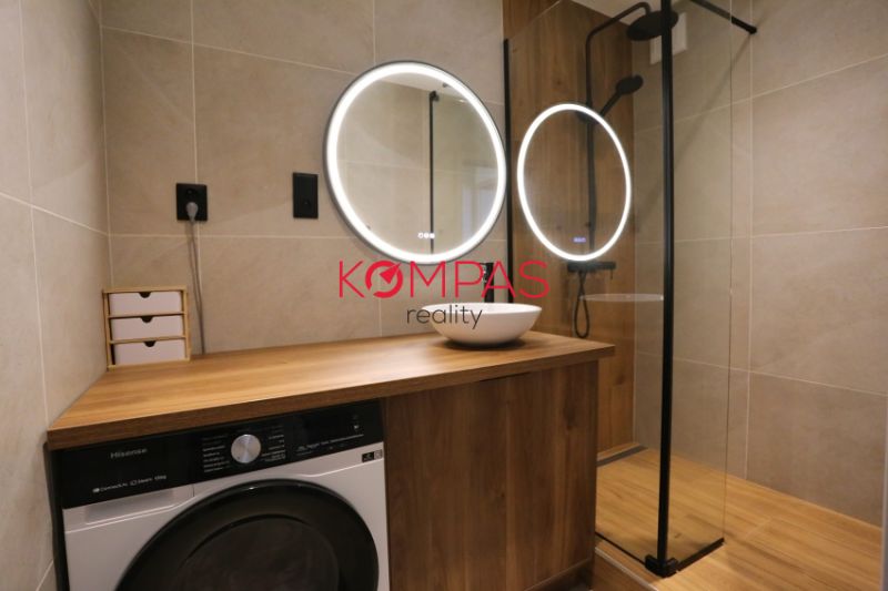 Bathroom in a 2-room apartment with a sink, shower, and floor with a wooden decor.