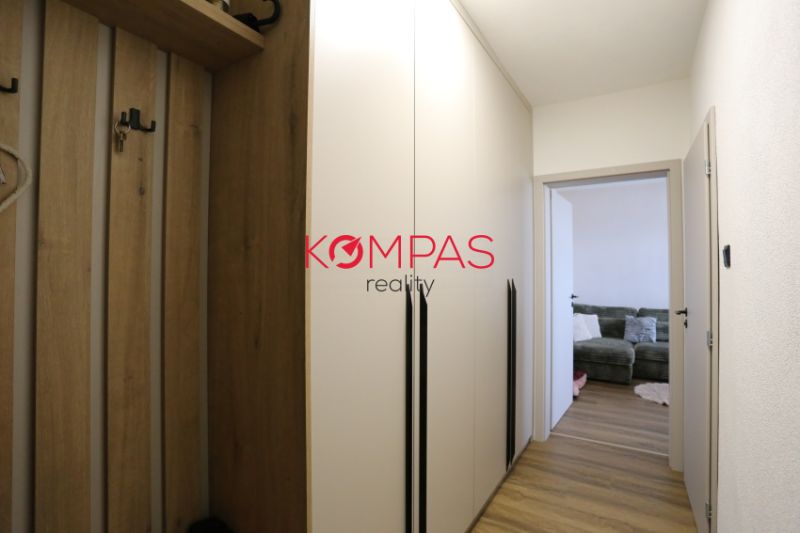 A hallway in a 2-room apartment with furniture and a wooden decor floor.