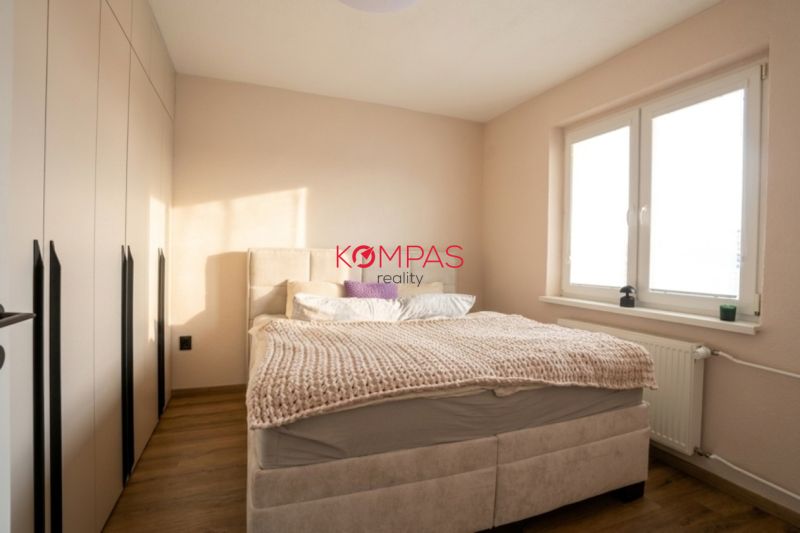 A bedroom in a two-room apartment with a wood-patterned floor and a large bed.