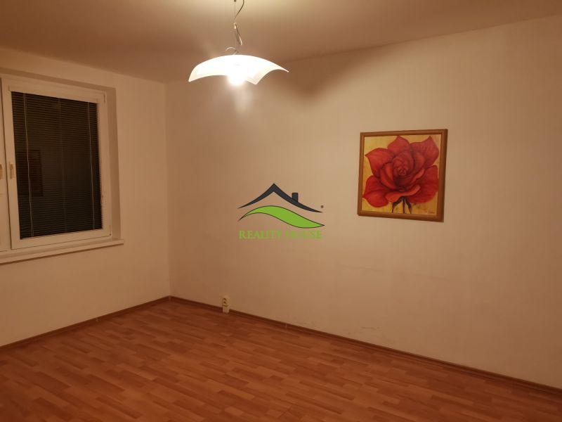 A room in a 3-room apartment with a wooden decor floor and a rose painting.