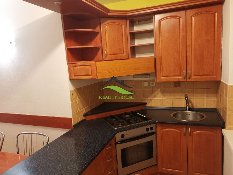 A kitchen in a 3-room apartment with wooden cabinets and ceramic tiles.