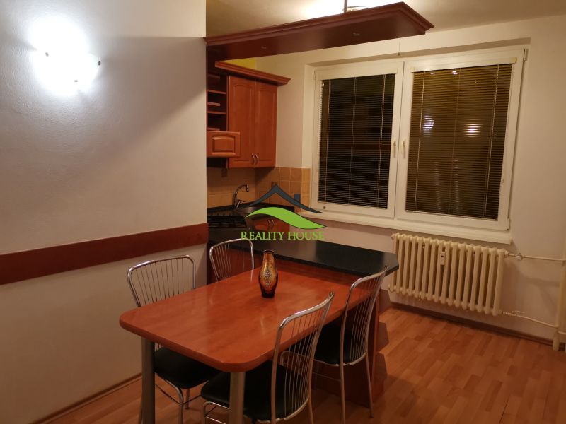 A kitchen in a 3-room apartment with a wooden decor floor and a dining table.