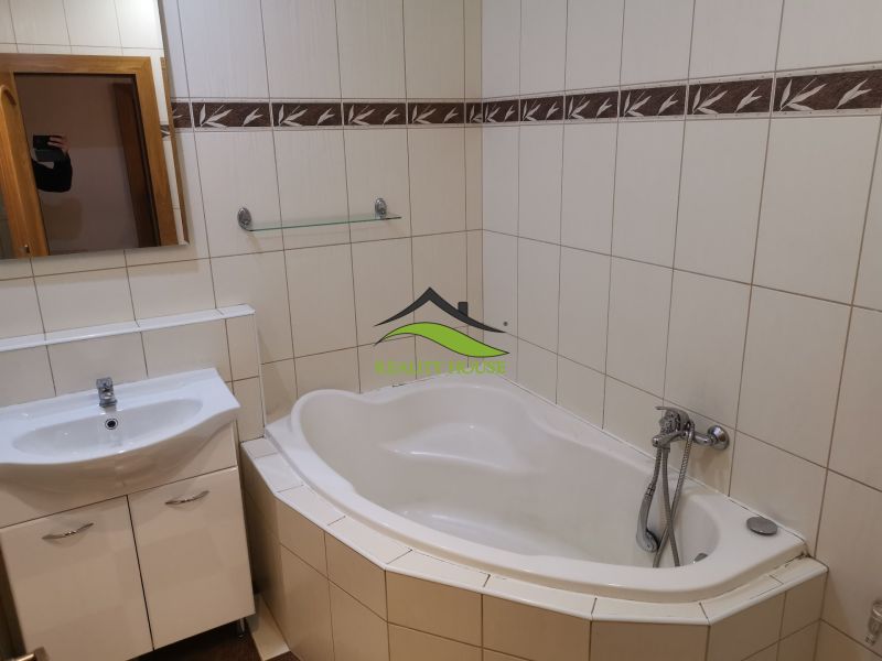 Bathroom with a bathtub and a sink, light tiles in a 3-room apartment.