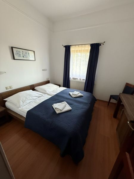 A room with a double bed, a blue blanket, and a wooden decor floor in hotels and guesthouses.