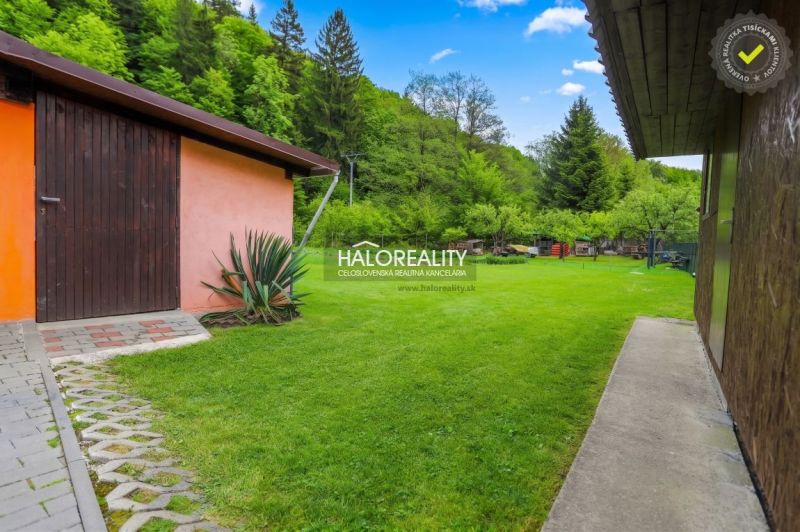 A family house in Dolná Mariková surrounded by a garden with a lawn and storage space.