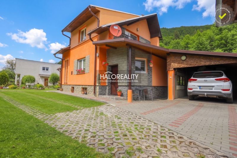 A family house in Dolná Mariková with a garage, lawn, and parking area in front of the house.