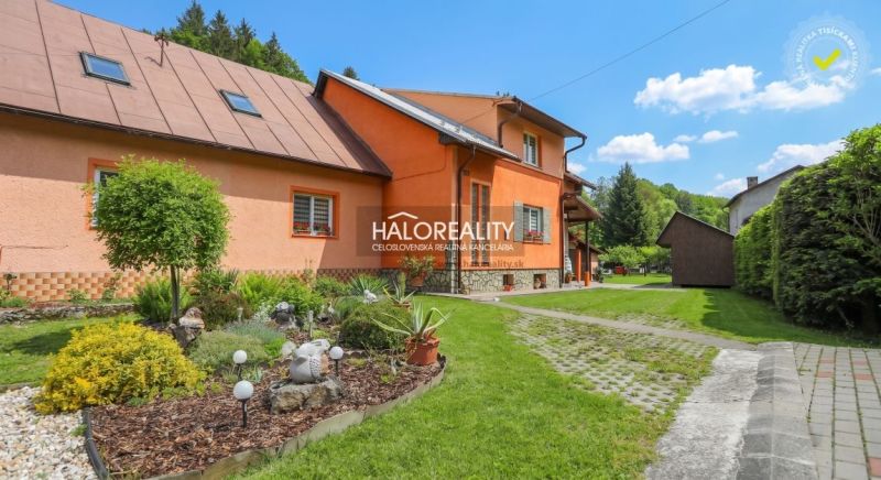 A family house in Dolná Mariková with a colorful facade surrounded by a green garden and a pathway.