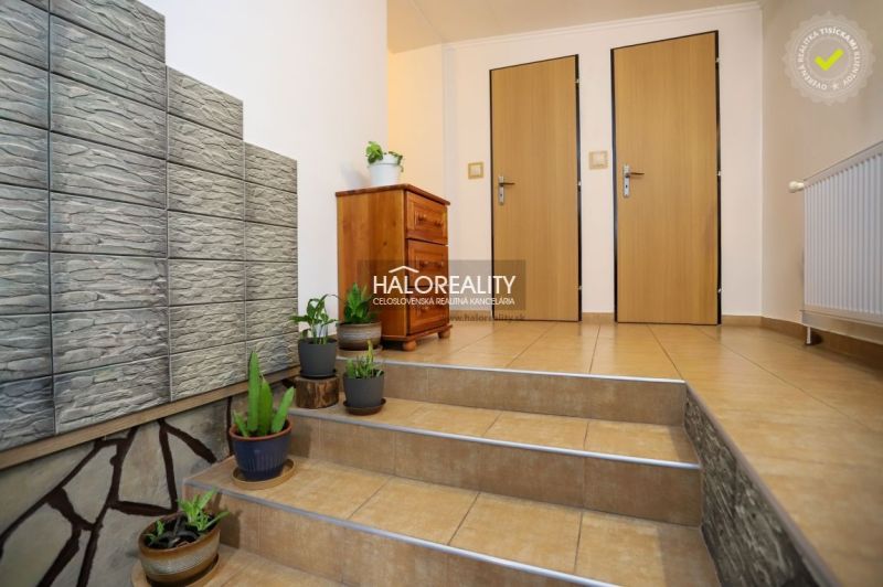 Interior of a family house with ceramic tiles, plants, and a cabinet on the stairs.