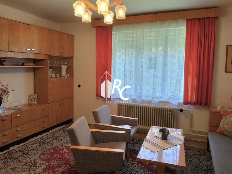 Living room with wood-patterned flooring, sofa, and armchairs in a family house.