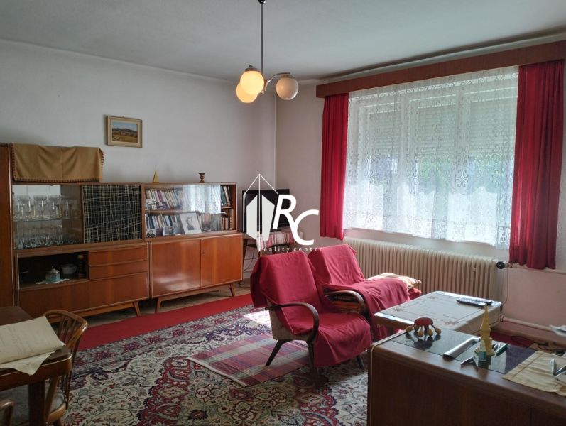 Living room in a family house with red armchairs and a glass display cabinet, wooden decor flooring.
