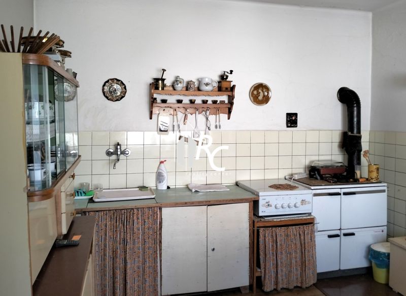 A kitchen in a family house with rustic cabinets and a classic stove.