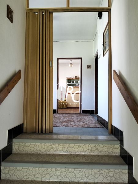 Hallway in a family house with wooden doors and tiled stairs.