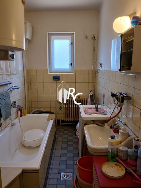 A bathroom in a family house with a bathtub, sink, and washing machine, surrounded by tiles.