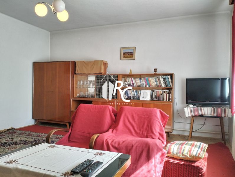 Living room in a family house with carpets, armchairs, and a television.