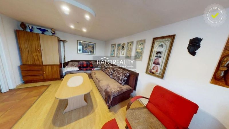 Living room in a family house with a sofa, wooden decor flooring, and wall paintings.