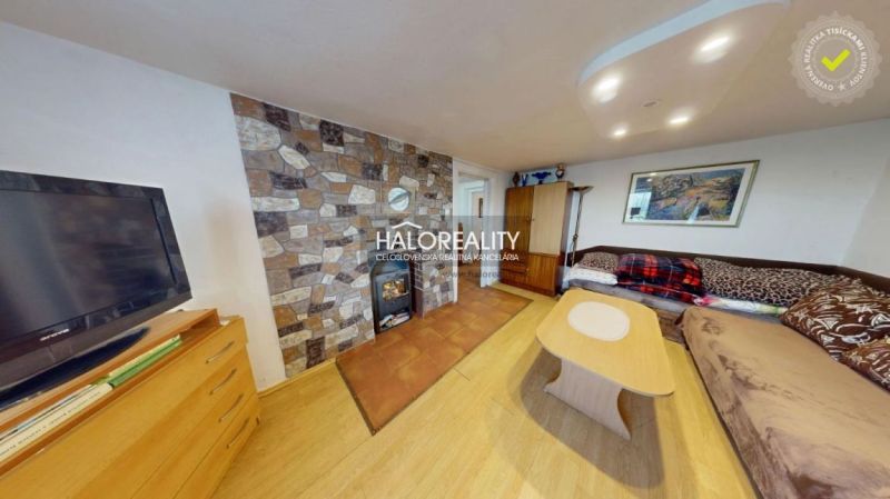 Living room with a tiled stove, sofa, and wooden decor flooring in a family house.