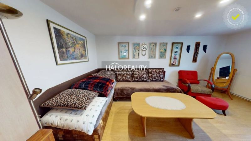 Living room in a family house with a sofa, armchairs, and paintings on the walls, floor with wooden decor.
