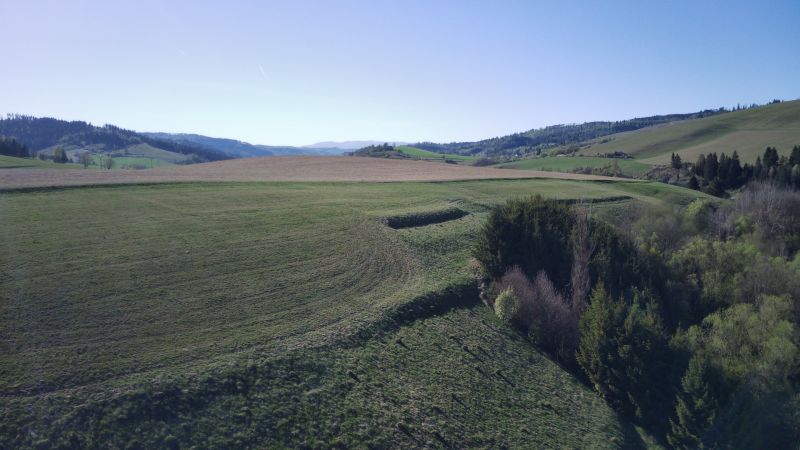 The landscape around Čierny Balog with agricultural and forest lands, on a clear day.
