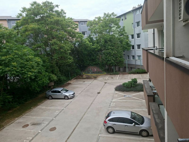 Parking lot on Športová Street in Dunajská Lužná with cars and greenery in the background.