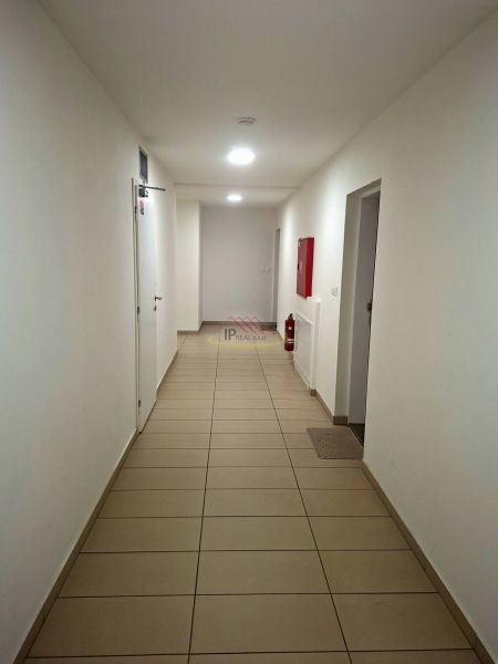 A corridor with white walls, tiles, and emergency equipment in a studio apartment.