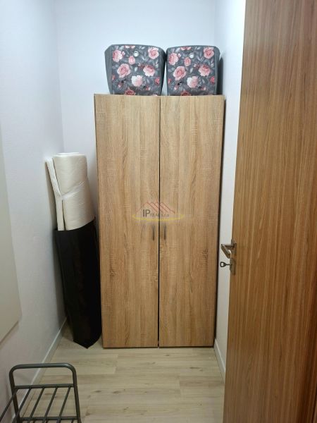 A storage cabinet with a wood decor and flowers on the boxes in a studio apartment.